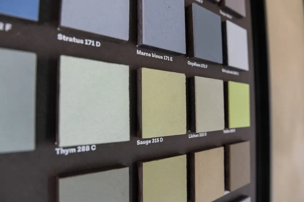 Sélection de plaques de béton ciré gris et ocre posées sur une table en bois pour apprécier le rendu de la matière par Nuances Peinture Décoration.