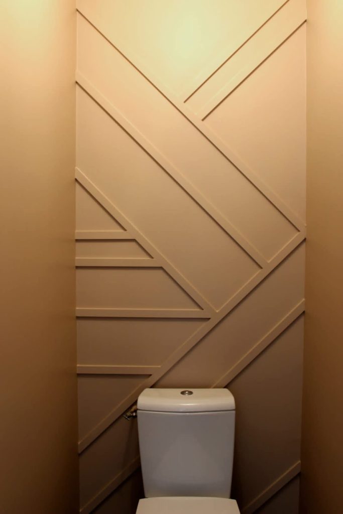 Décoration murale géométrique avec tasseaux de bois peints dans un ton beige chaleureux pour des WC originaux réalisée avec de la peinture interieure par Nuances Peinture Décoration