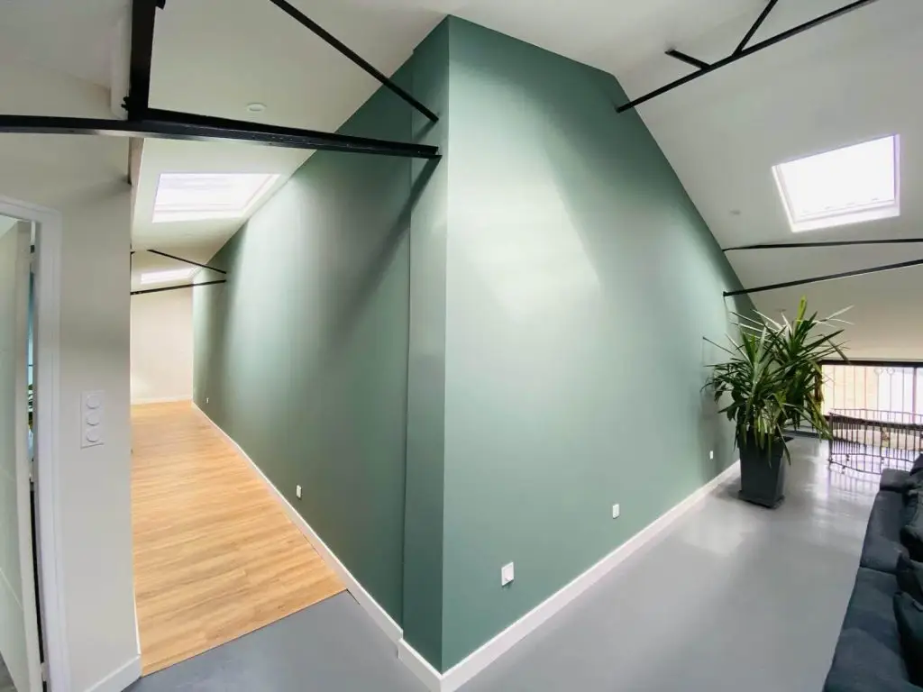 Rénovation de peinture intérieure dans un espace de vie moderne avec un grand pan de mur peint en vert sauge réalisation par Nuances Peinture Décoration