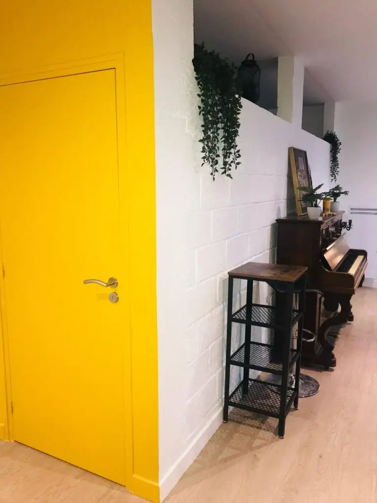 Peinture intérieur - Porte intérieure peinte en jaune vif apportant une touche moderne et colorée dans un salon, par un artisan peintre à Dinan par Nuances Peinture Décoration
