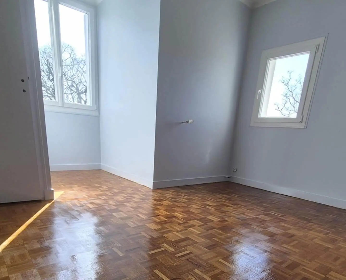 Rénovation complète d'une pièce lumineuse avec peinture intérieure claire sur les murs et vitrification d'un parquet en mosaïque de bois à Dinan.