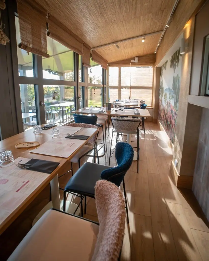 Revêtement muraux - Aménagement et peinture intérieure d'une salle de restaurant lumineuse avec fresque murale végétale, réalisée près de Dinan par Nuances Peinture Décoration.