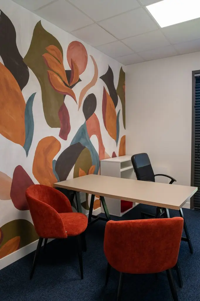 Revêtement Muraux -Décoration murale d'un espace de travail avec une peinture intérieure artistique aux motifs abstraits et fauteuils en velours terracotta par Nuances Peinture Décoration.